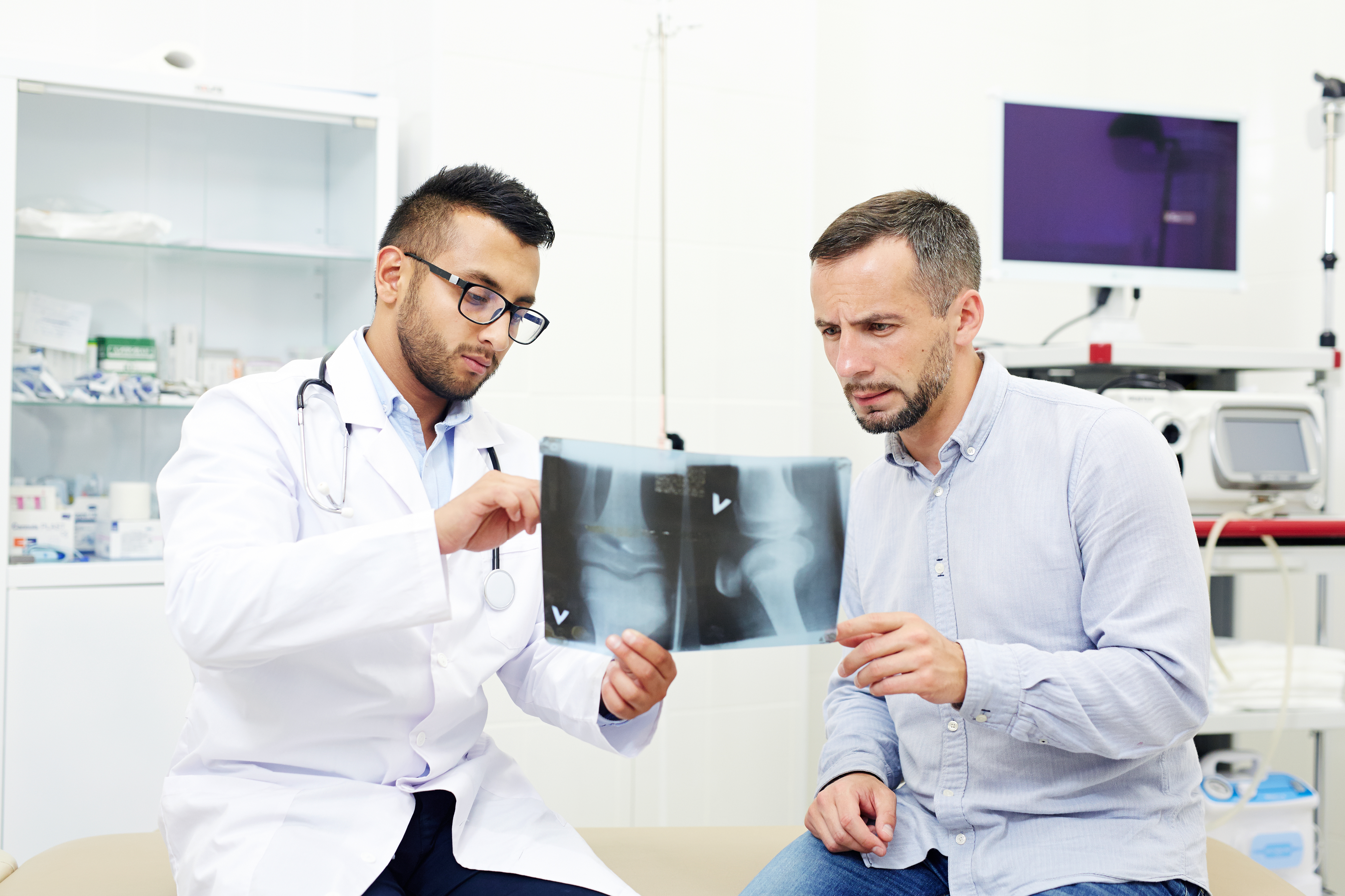 Radiologist and young man discussing x-ray images of joints